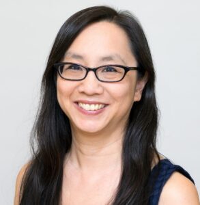 Headshot of Kim Chan. Kim appears from the chest up and wears a black, sleeveless v neck top and black framed glasses.