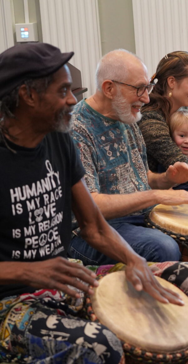 Color image of diverse people playing African drums in a workshop.